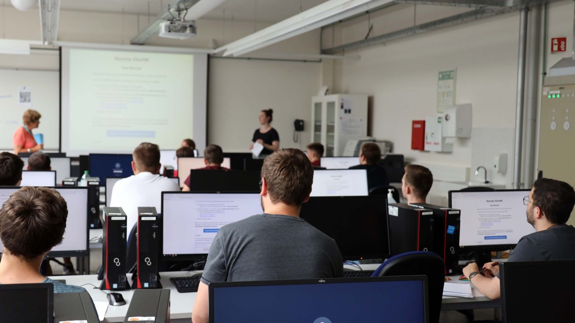 Studierende sitzen vor Computern für digitale Prüfung