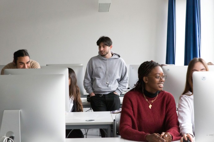 Studierende arbeiten gemeinsam vor Bildschirmen