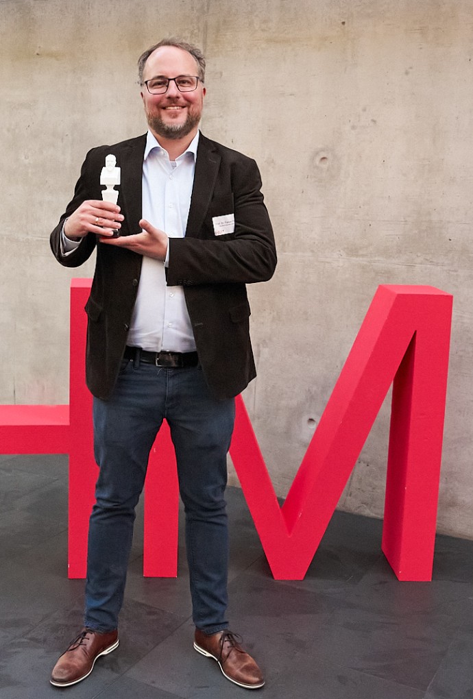 Auf dem Bild ist der Oskar-Preisträger, Prof. Dr. Fabian Flohr, für Forschung 2025 mit dem Oskar in der Hand zu sehen.