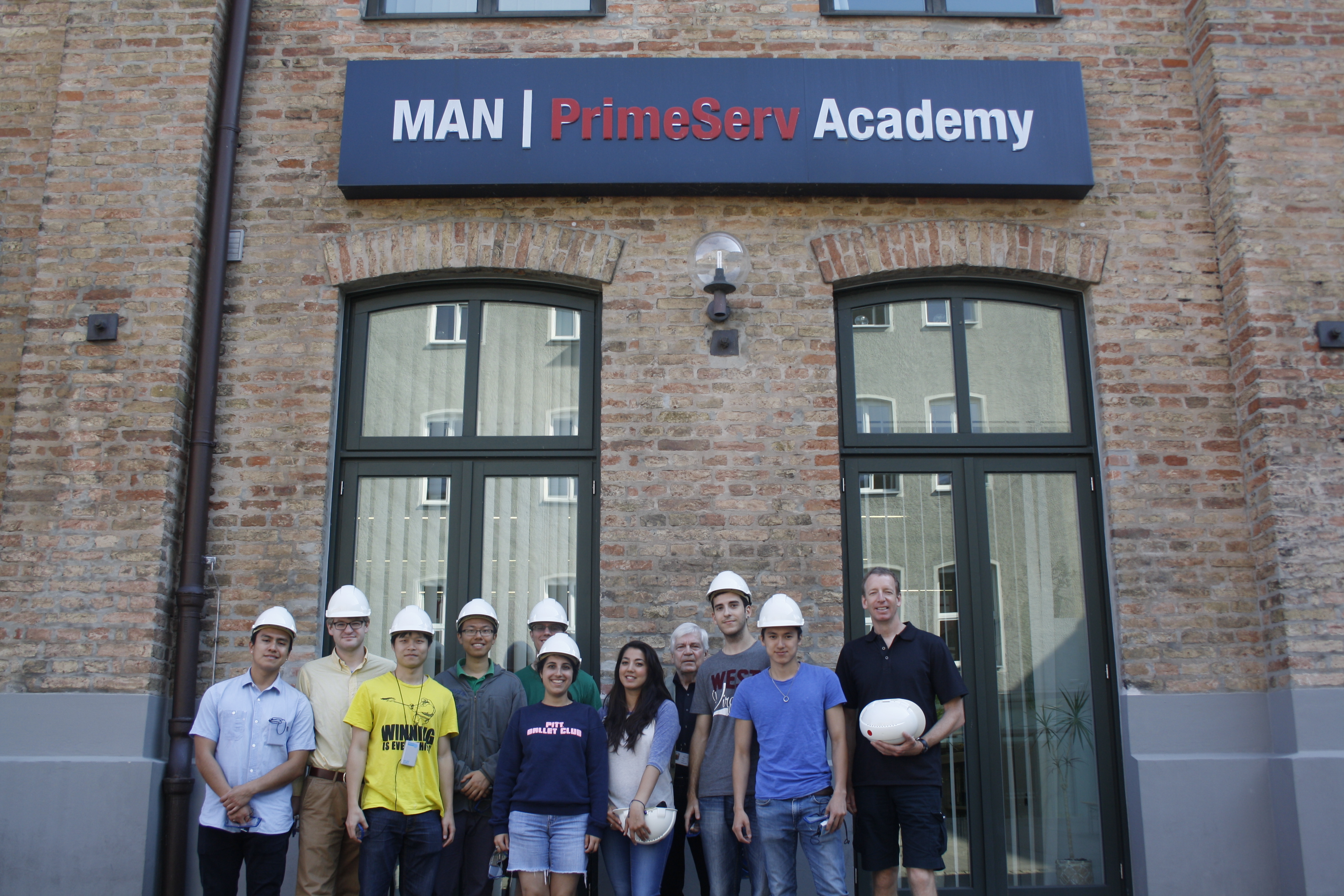 Students on a summer school trip to MAN PrimeServ Academy, standing in front of the companys sign 