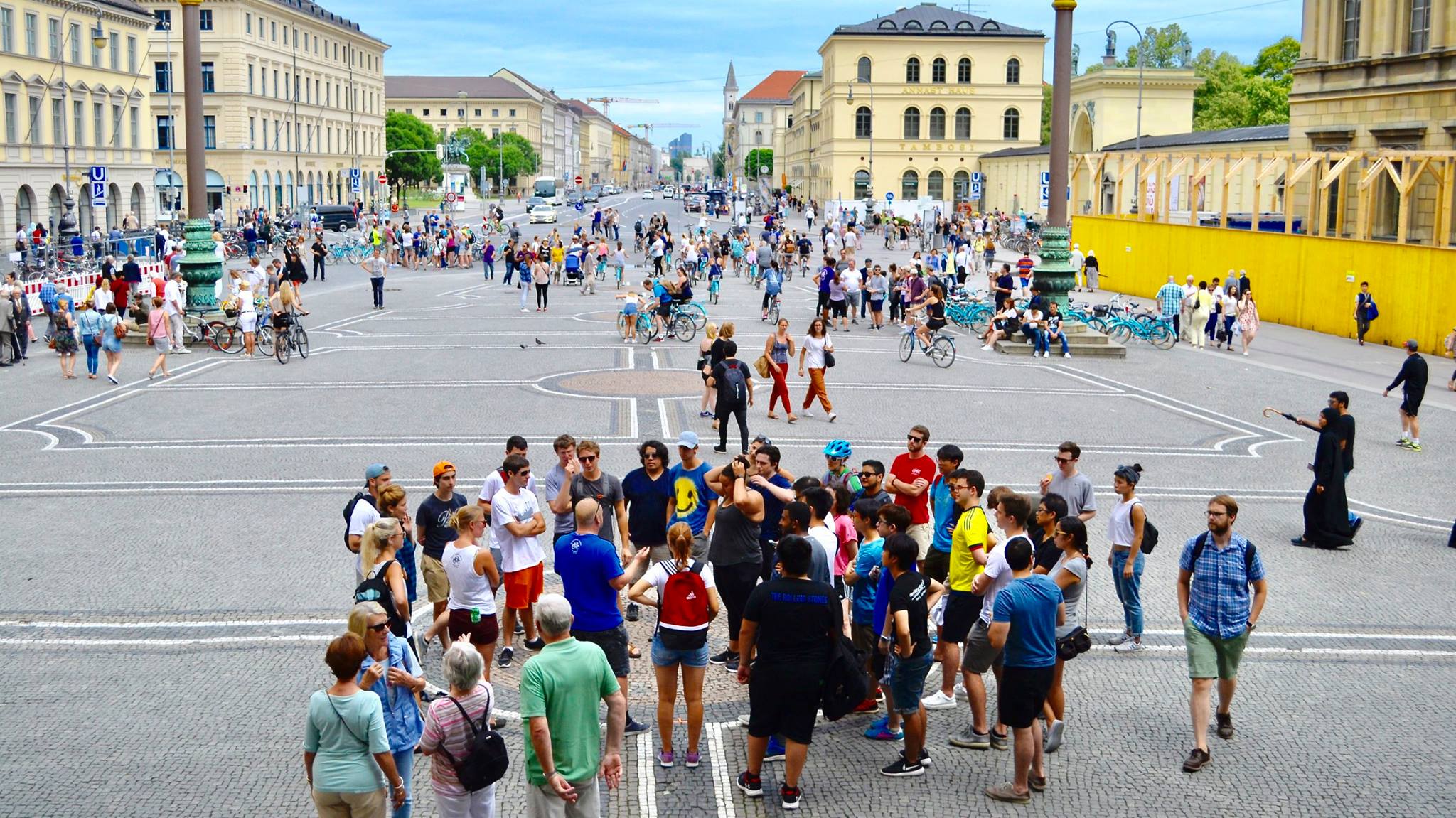 Summer school students standing at Odeonsplatz in Munich during their Munich Bike Tour on a sunny day with blue sky