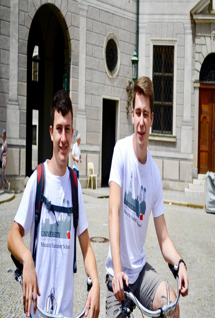 Two Summer School students with Summer School t-shirts can be seen in the picture, with a building in the background.
