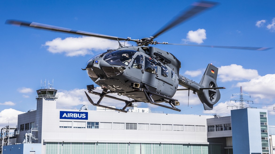 An Airbus helicopter in flight on a sunny day with blue sky and clouds in the background