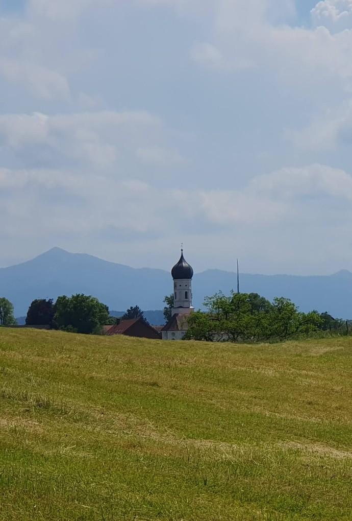 Landschaft mit Kirche vor den Bergen