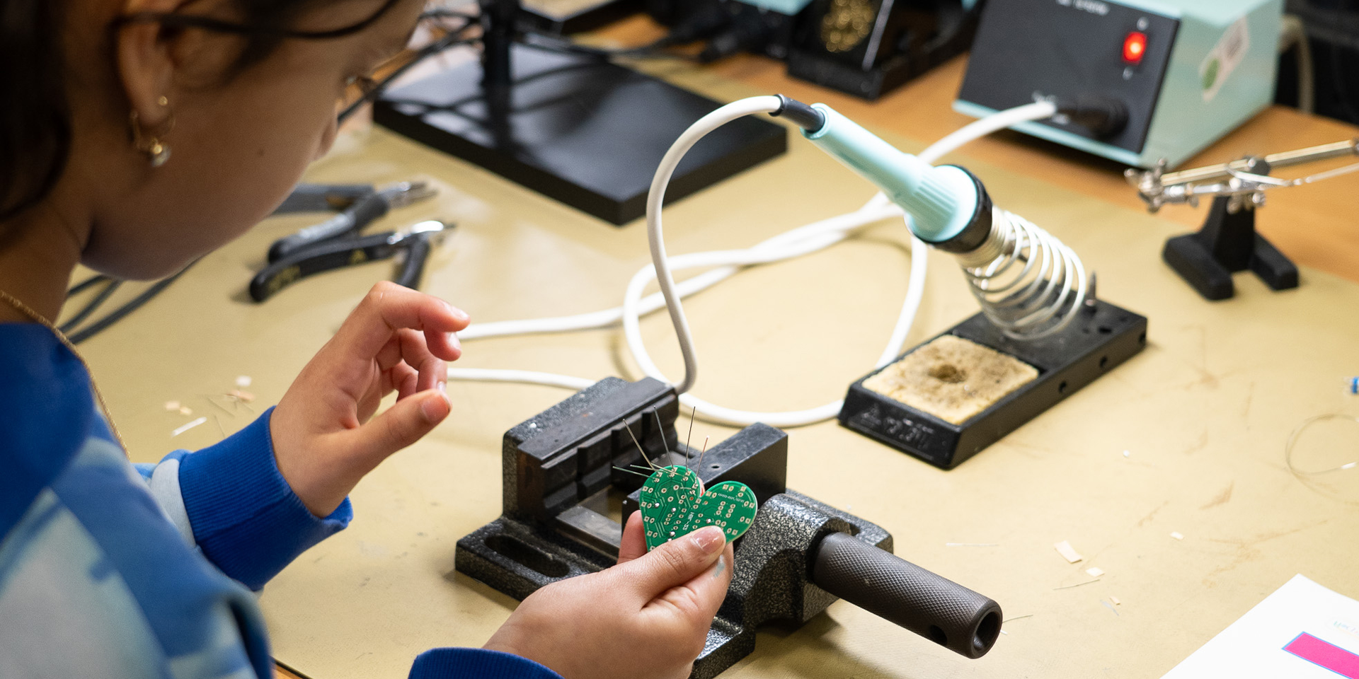 Ein Mädchen lötet an einer Herzplatine 