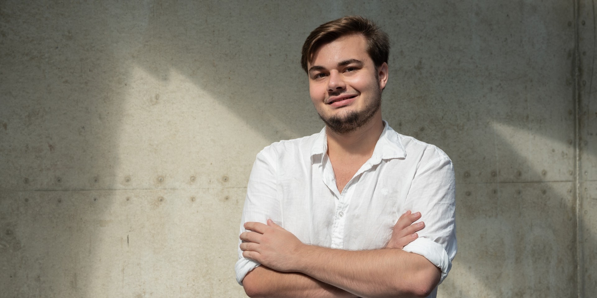 Nils steht in der Hochschule und verschränkt die Arme