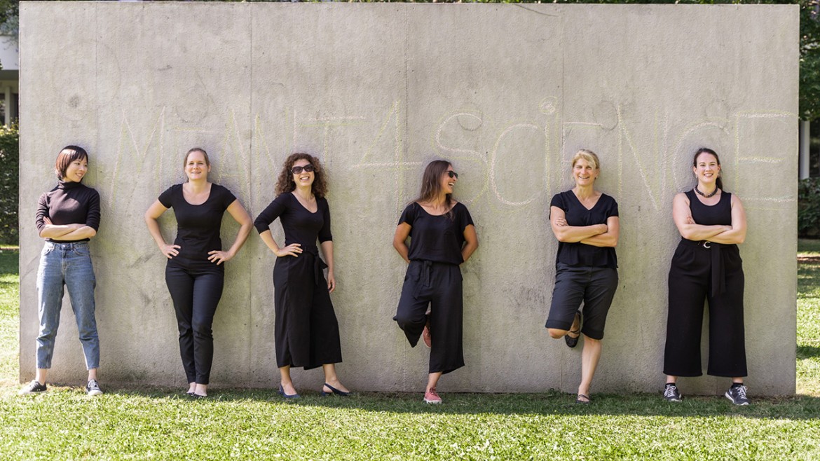 Sechs Frauen stehen vor einer Betonwand im Grünen