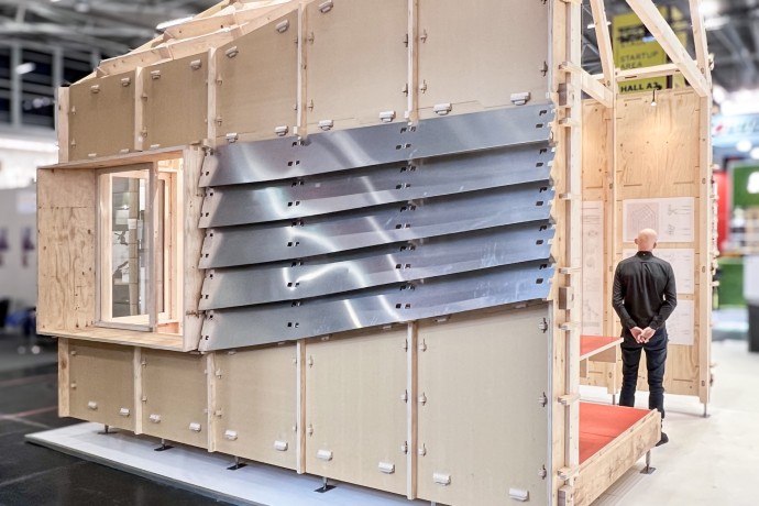 Ein Mensch steht im Prototypen eines Holzhauses zum Zusammenstecken