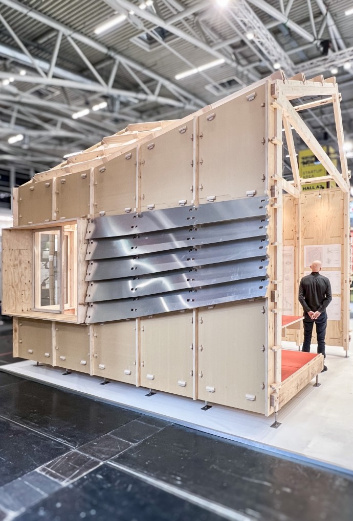 Ein Mensch steht im Prototypen eines Holzhauses zum Zusammenstecken