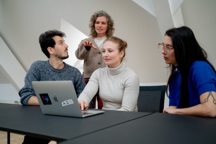 Wissenschaftlerinnen und Wissenschaftler sitzen vor Laptop und diskutieren