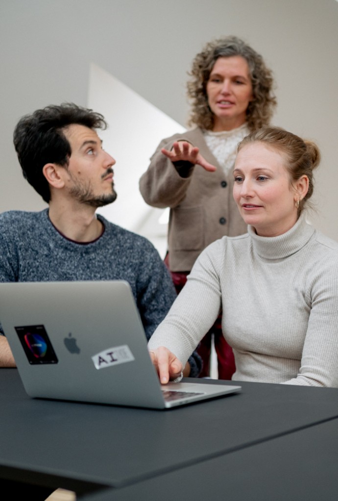 Wissenschaftlerinnen und Wissenschaftler sitzen vor Laptop und diskutieren