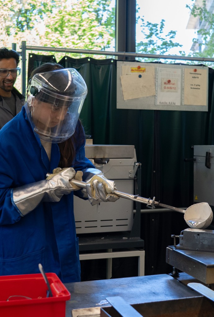 Teilnehmerin am Girls Day der HM gießt heißes Metall in Form