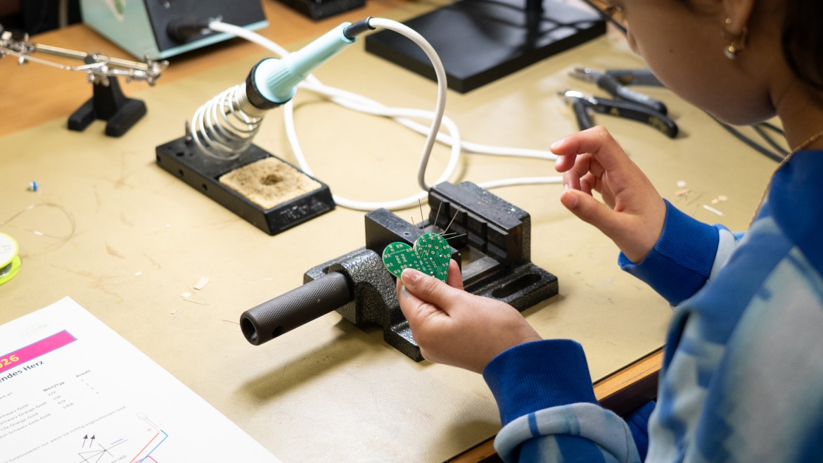 Mädchen lötet eine herzförmige Platine mit Leuchtdioden