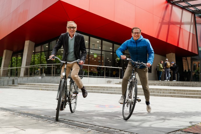Klaus Kreulich und Jörg Finger sitzen auf dem Fahrrad vor dem roten Würfel