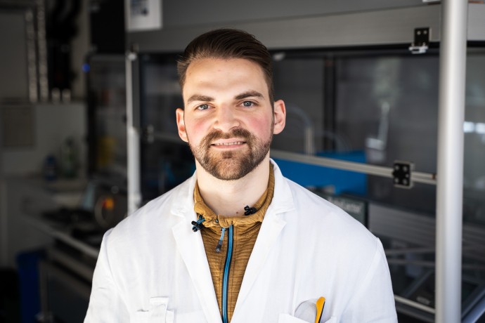 Wissenschaftlicher Mitarbeitr Patrik Hanisch lächelt in seinem Labor in die Kamera