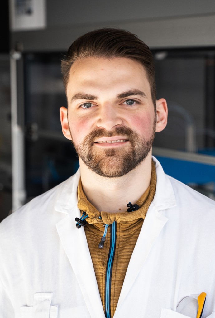 Wissenschaftlicher Mitarbeitr Patrik Hanisch lächelt in seinem Labor in die Kamera