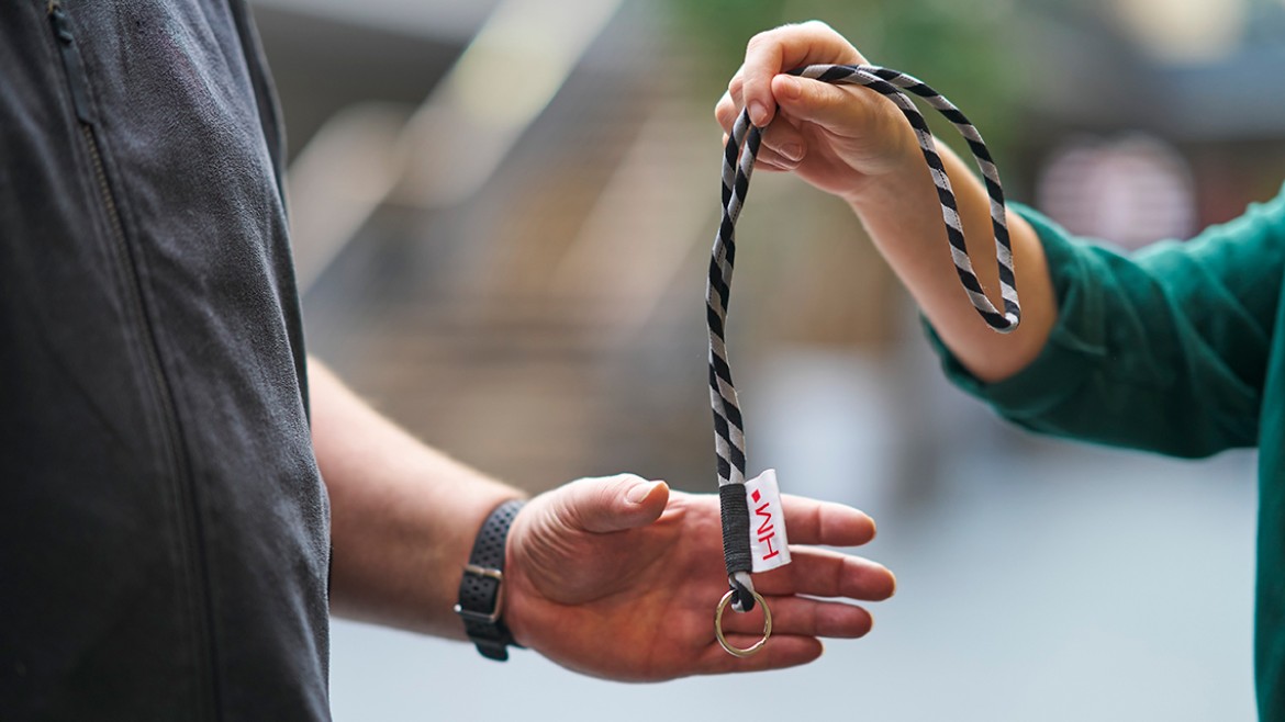 Übergabe eines Schlüsselbands von einer Person zu einer anderen.