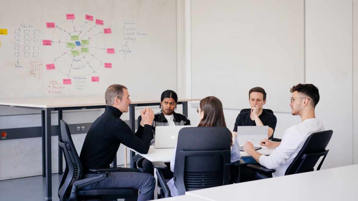 Mehere Personen sitzen um einen Tisch.