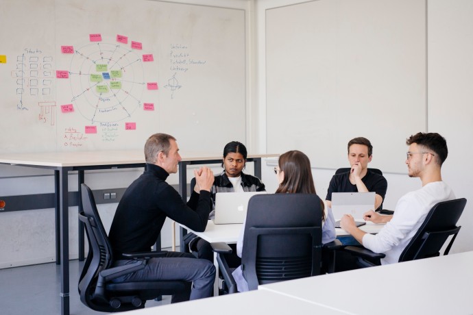 Forschungsdatenmanagement (Foto: Hochschule München / Ulrike Myrzik) Mehere Personen sitzen um einen Tisch.