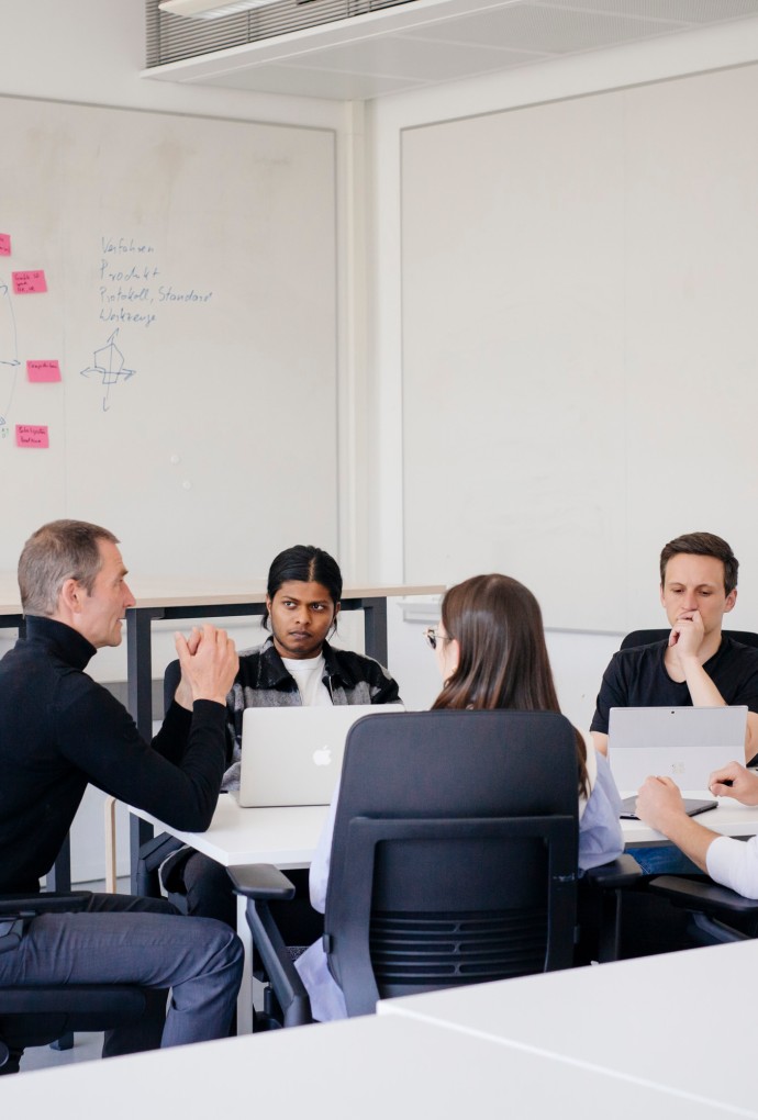 Forschungsdatenmanagement (Foto: Hochschule München / Ulrike Myrzik) Mehere Personen sitzen um einen Tisch.