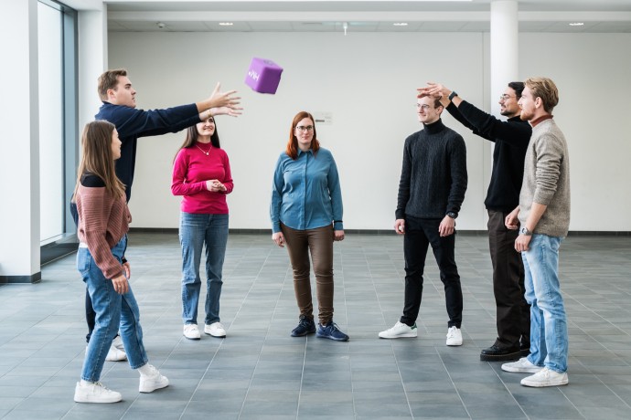 Mehrere Personen stehen in einem Kreis und werfen sich eine Ball zu 