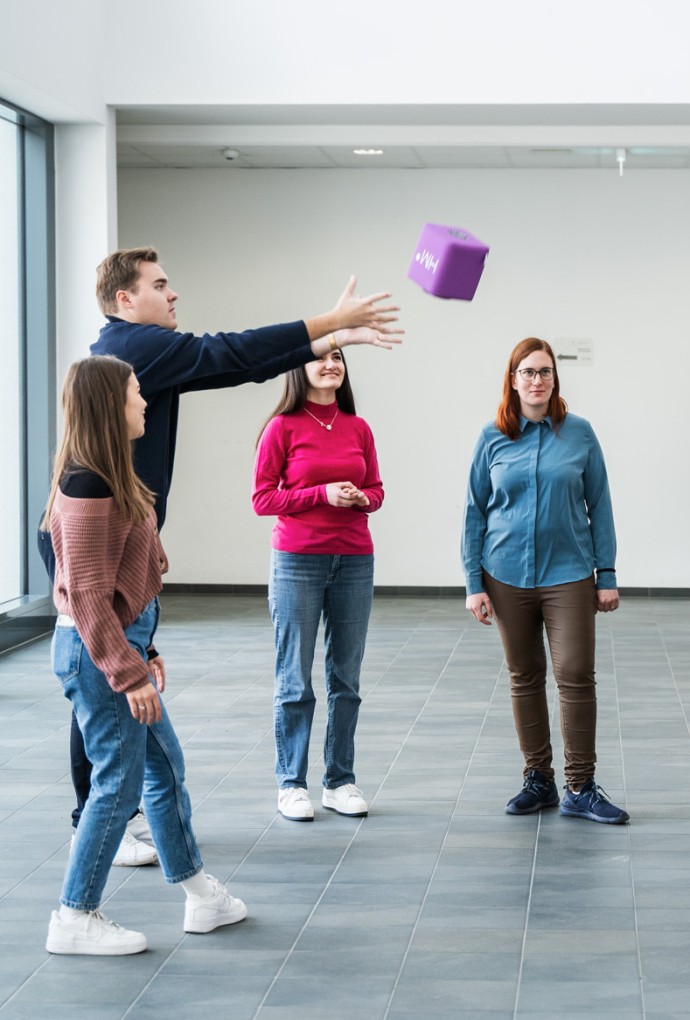 Mehrere Personen stehen in einem Kreis und werfen sich eine Ball zu 