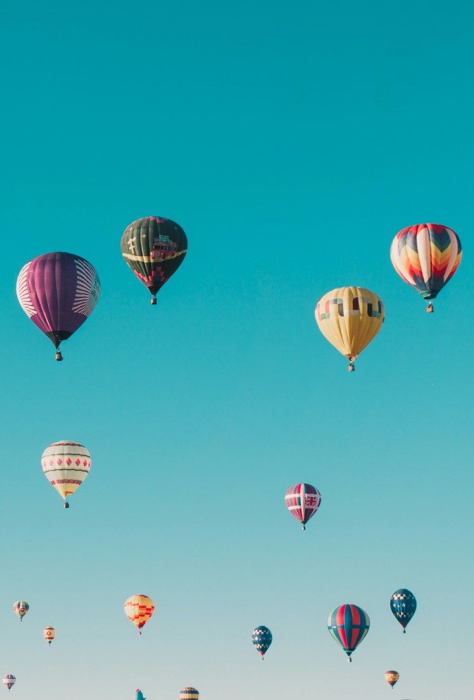 Vielle bunte Heißluftballone fliegen am blauen Himmel