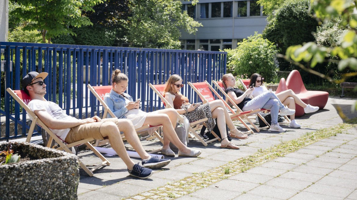 Studierende im Liegestuhl mit dem Handy in der Hand.