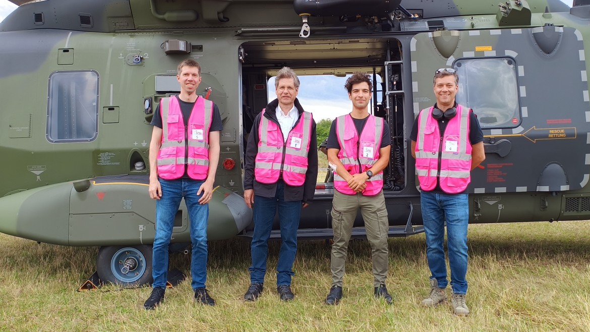 Brandbekämpfung in der Praxis: HM-Mitarbeitende vor einem Hubschrauber der Staatlichen Feuerwehrschule Würzburg