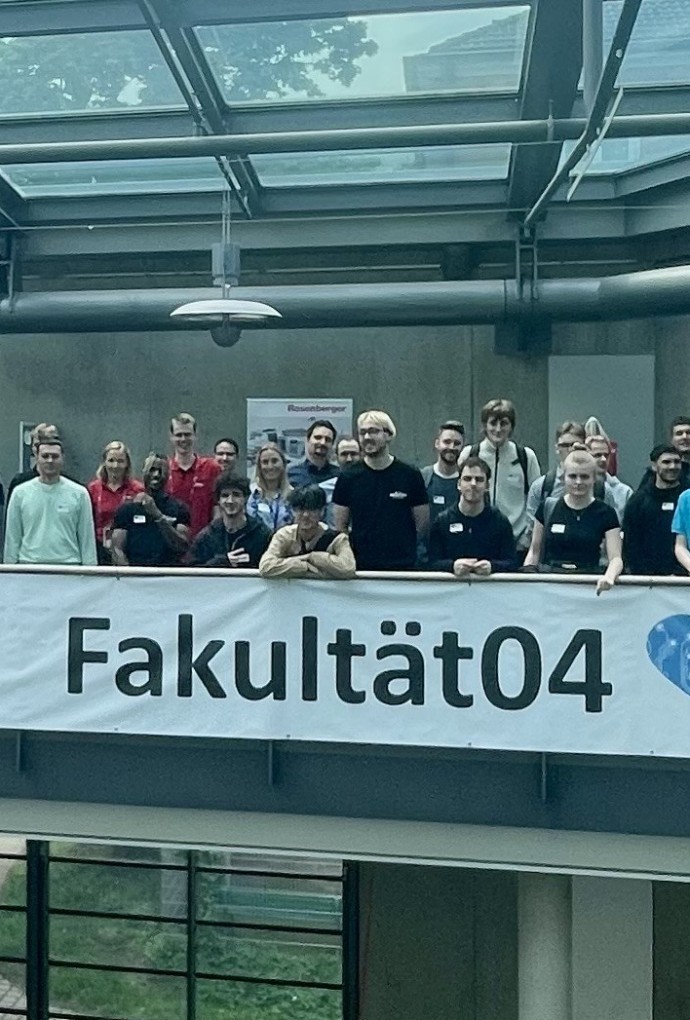 Firmenvertreter, Studierende und Lehrende posieren vor einem Banner mit der Aufschrift 