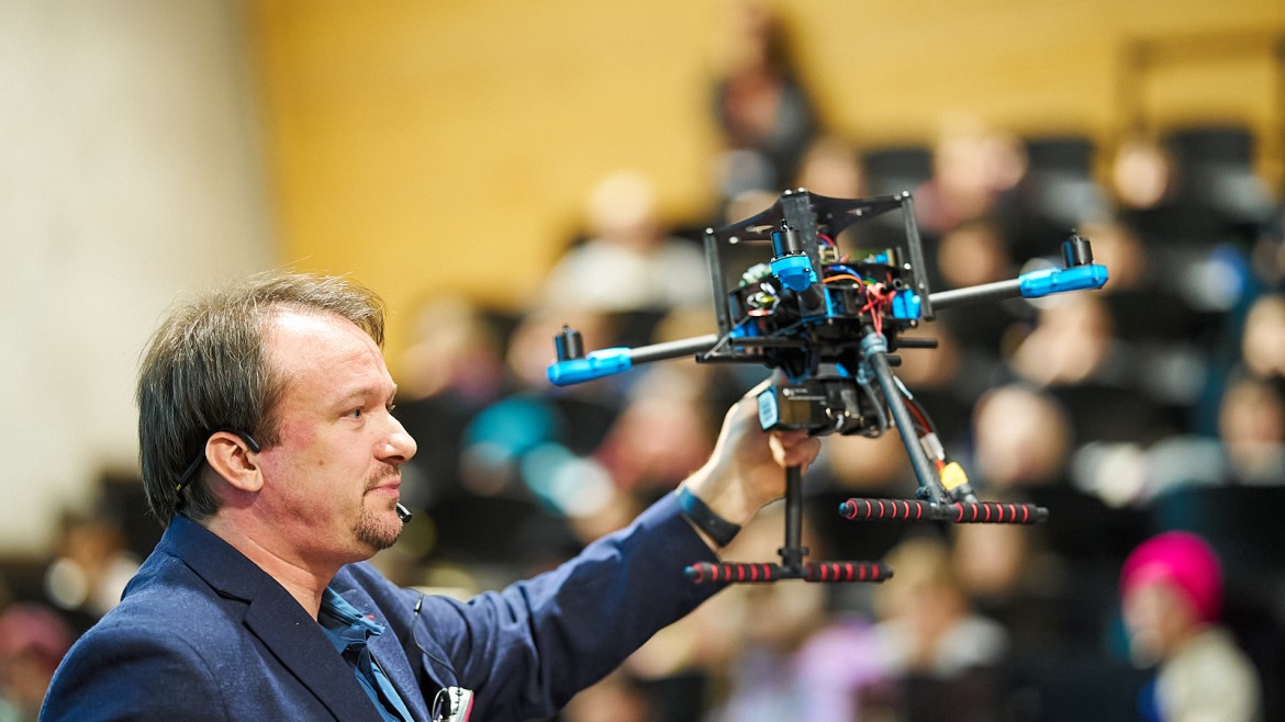Prof. Dr. Benjamin Kormann zeigt Kindern eine Drohne während der KinderUni