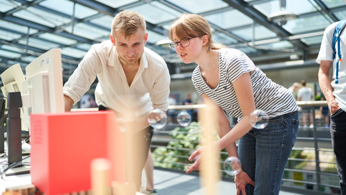 Ein Student spricht mit einer Studentin über sein Projekt auf der Projektvernissage an der Hochschule München