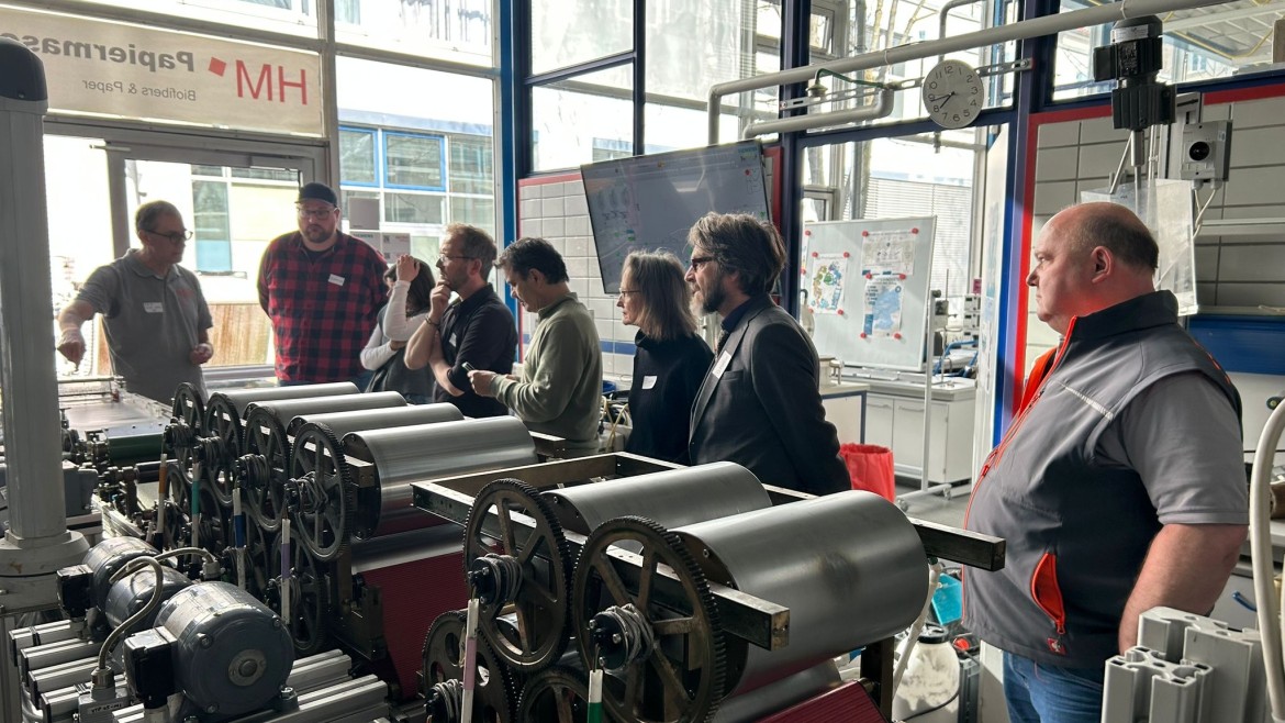 Gruppe von Werklehrerinnen und -lehrern an der Papiermaschine der Hochschule München