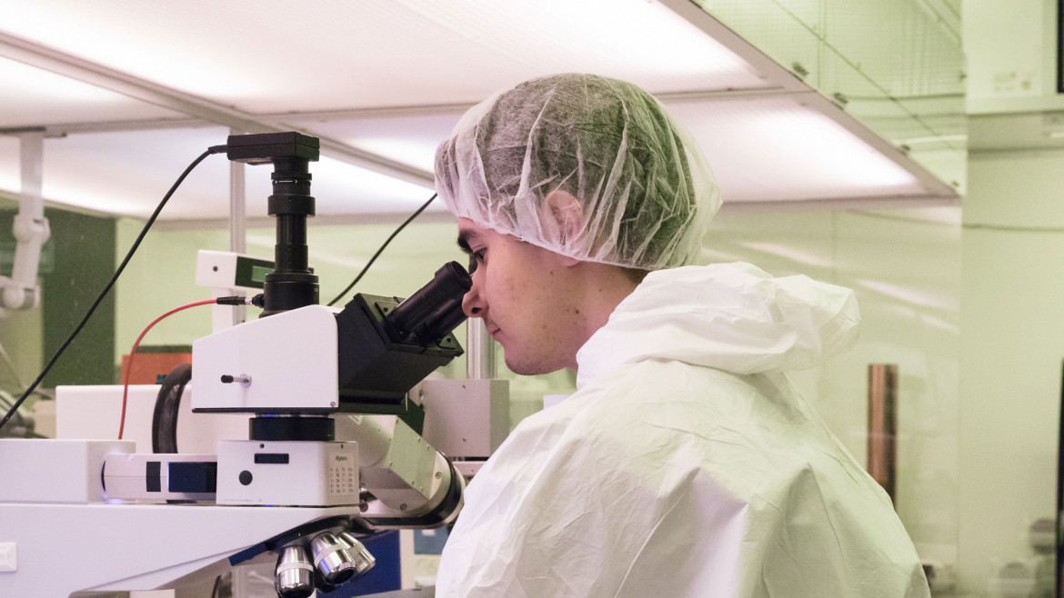 Student im Reinraum / Labor für Mikrosystemtechnik vor Mikroskop beim Betrachten einer Probe