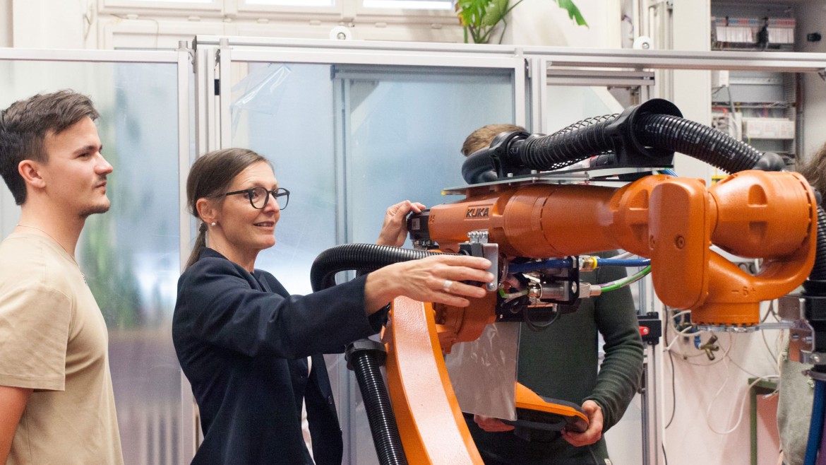 Professorin erläutert Studenierenden ein Detail an einem Roboterarm, Labor für Automatisierung und Robotik