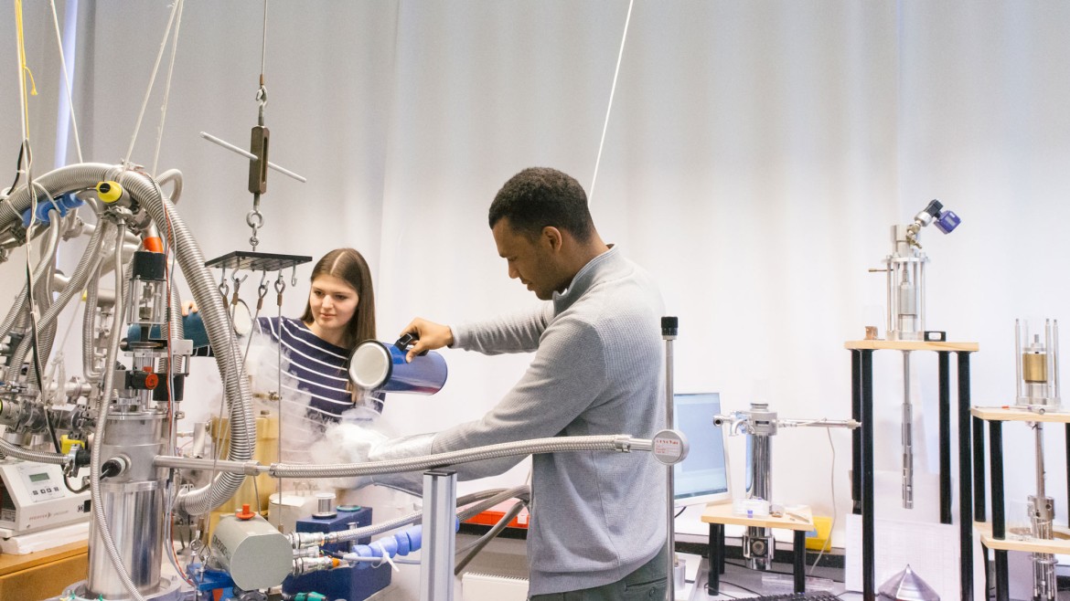 Zwei Studierende füllen Flüssigstickstoff in Behälter am Versuchsaufbau im Labor für Festkörperphysik