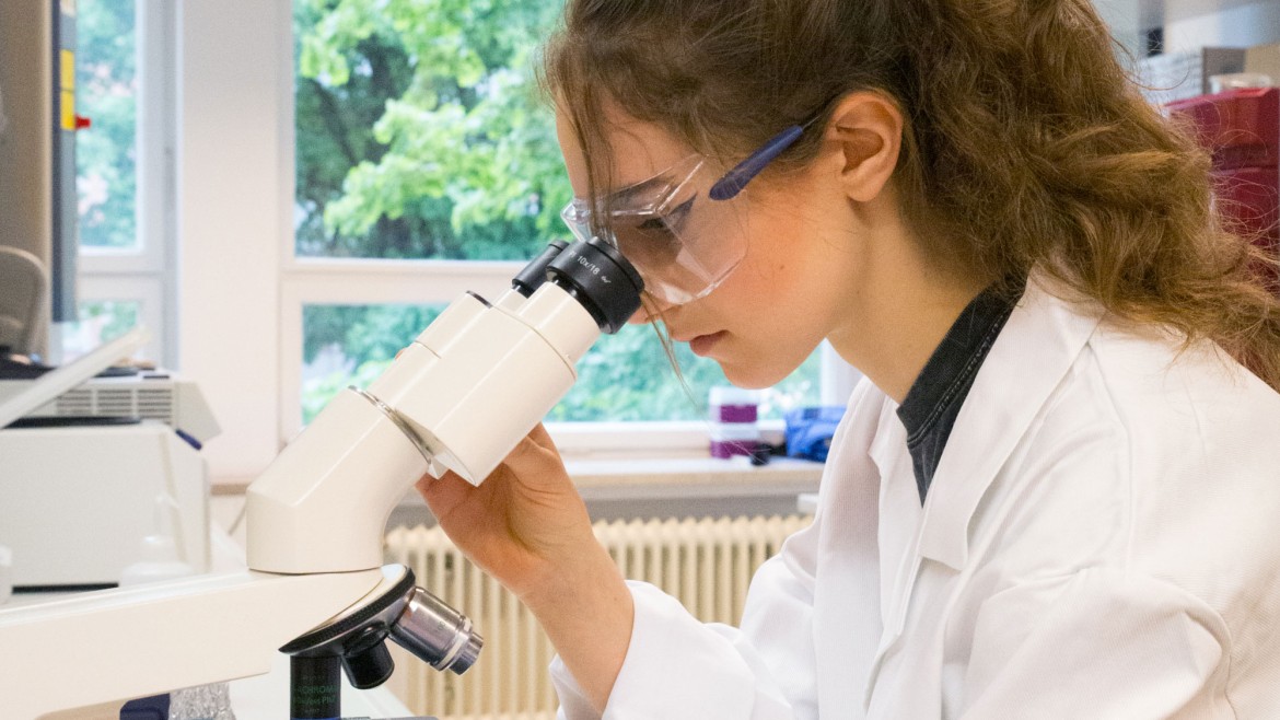 Studentin am Mikroskop im Labor für Biochemie / Mikrobiologie