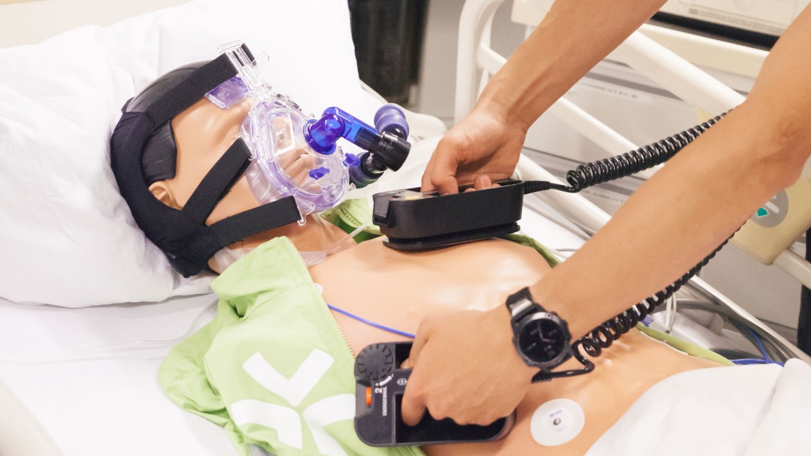 Student demonstriert Arbeit mit Defibrilator am Dummy im BioMedLab