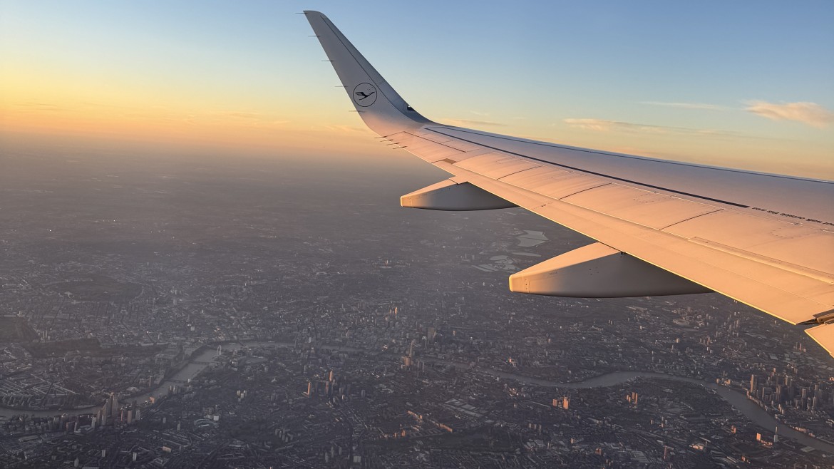 Blick aus einem Flugzeug auf die Tragfläche vor einem Sonnenaufgang
