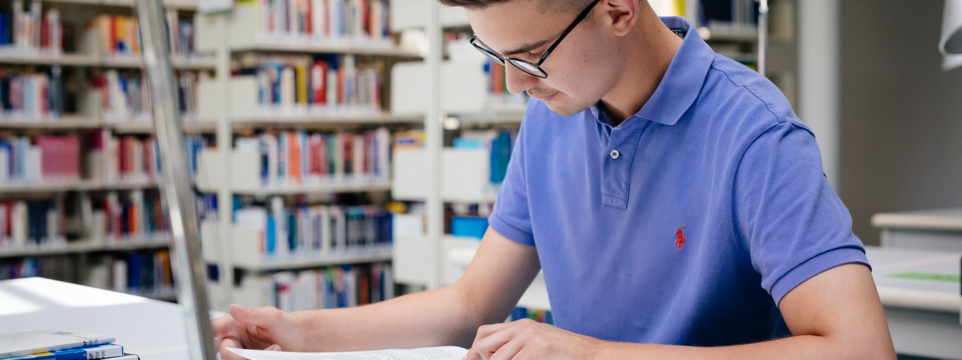 Student in der Bibliothek mit Büchern