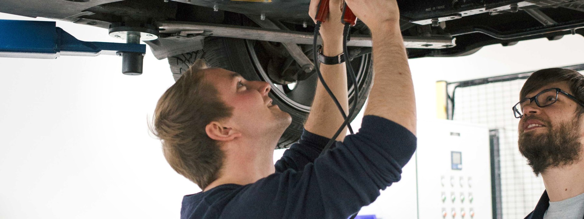 2 Personen arbeiten an einem aufgebockten Auto